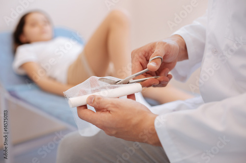 Nice male doctor cutting a bandage