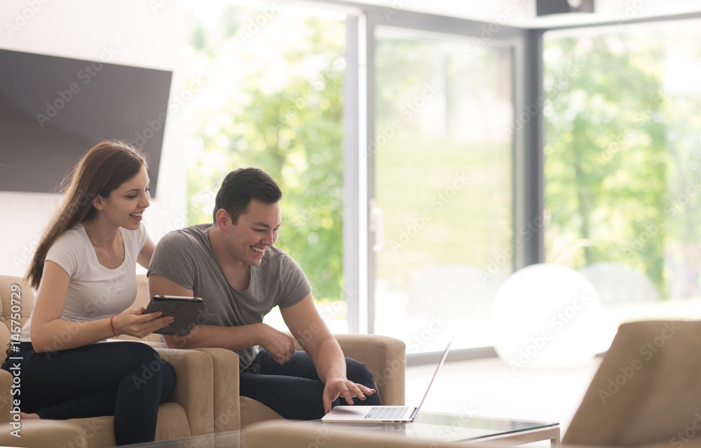couple relaxing at home with tablet and laptop computers couple relaxing at home with tablet and laptop computers