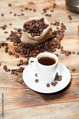cup of coffee with grains on the wooden background