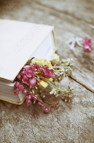 Closed book with flowers on wood table background