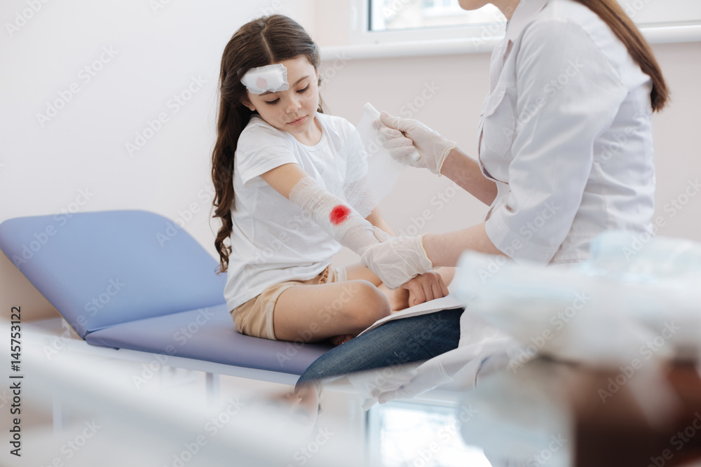 Professional nice traumatologist wrapping the bandage around the wound