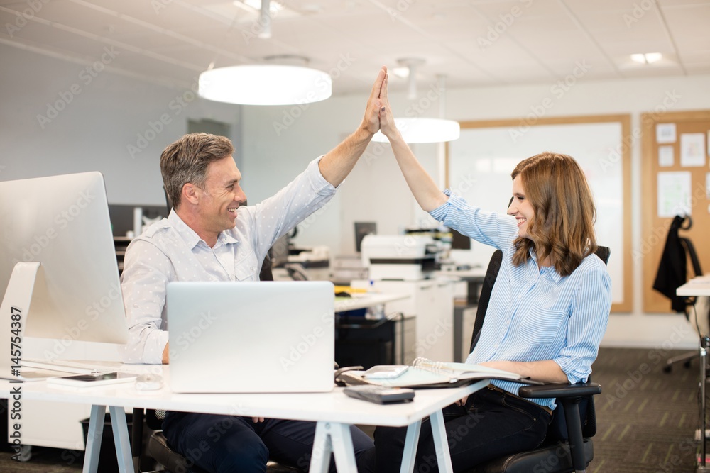 Obraz premium Happy business colleagues giving high five to each other