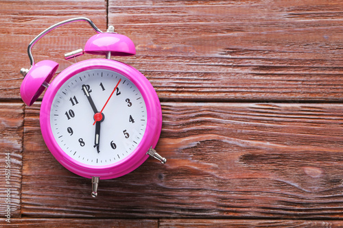 Pink alarm clock on brown wooden table