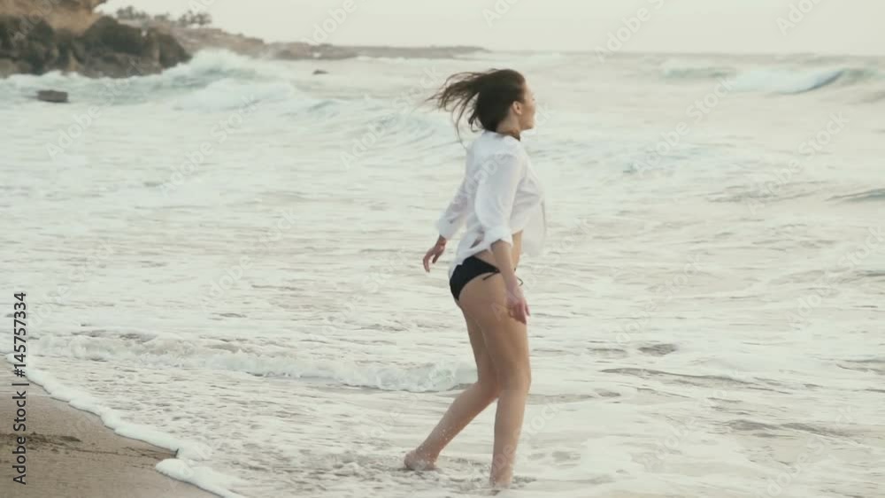 Beautiful brunette walking on the coast of the ocean Beautiful brunette walking on the coast of the ocean