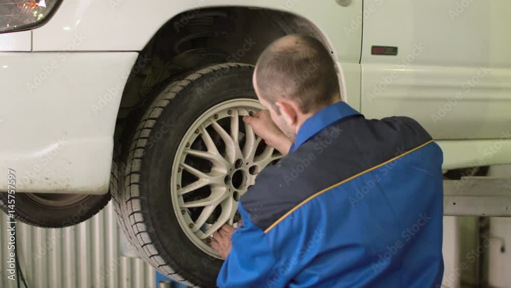 Car mechanic is checking car wheels on crossover in car repair service Car mechanic is checking car wheels on crossover in car repair service