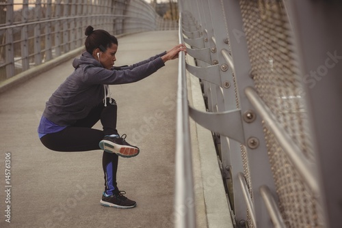 Woman exercising by railing on bridge photo