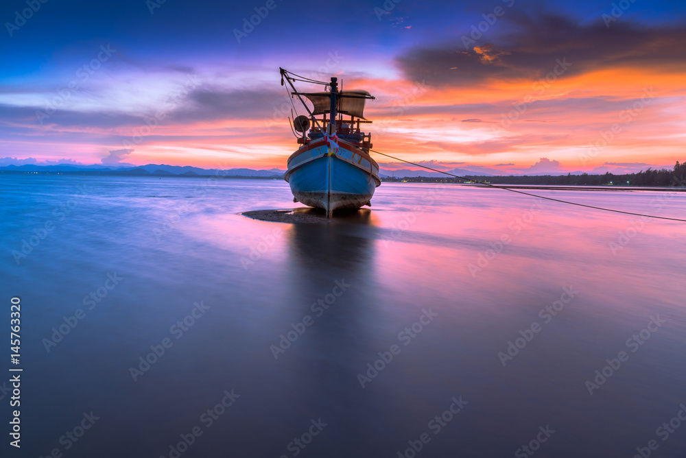 Fishing boat in tropical beach with beautiful sunset time.