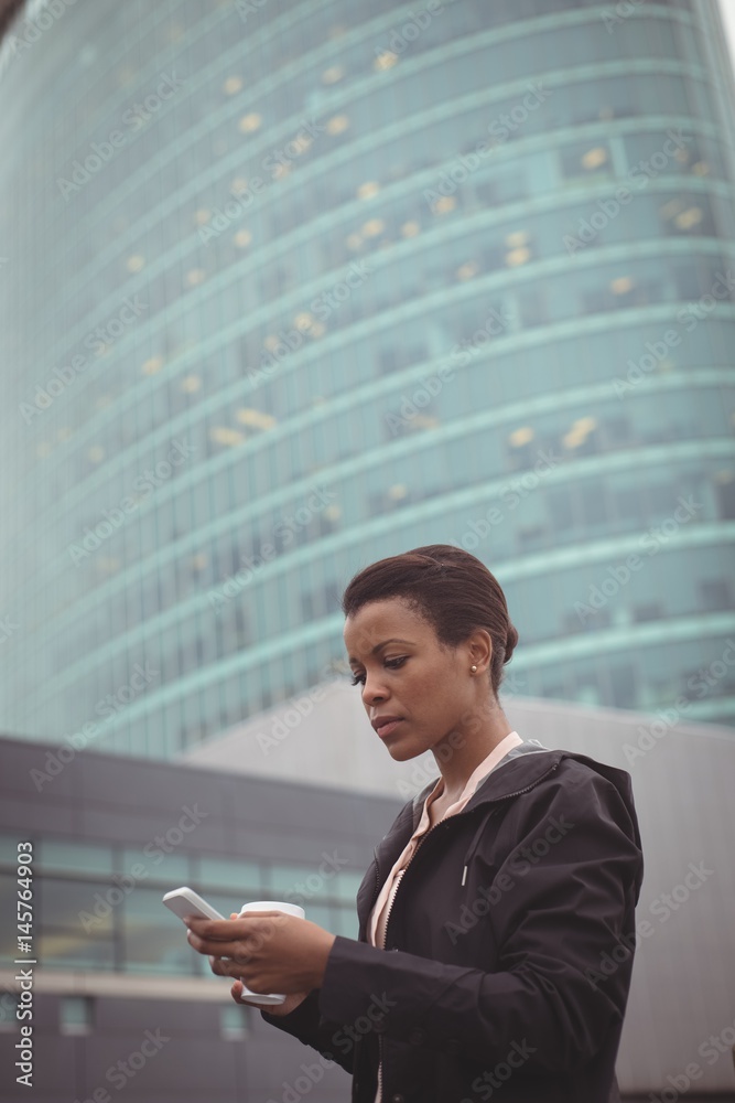Businesswoman using mobile phone against modern building Businesswoman using mobile phone against modern building