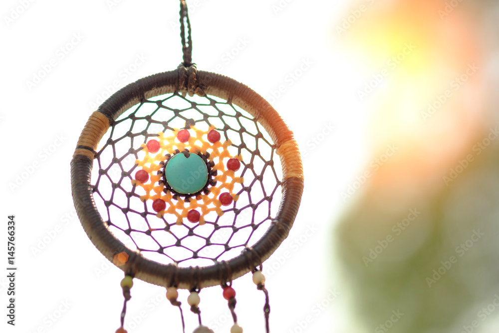 Obraz premium Dreamcatcher on the tree with green natural blurred bokeh background.