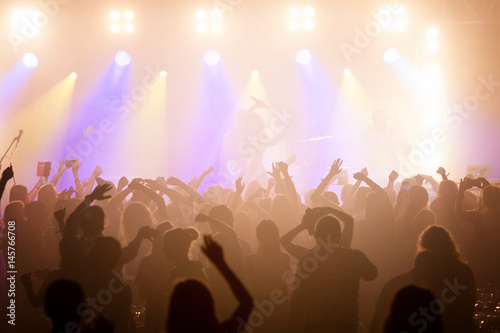 The audience at a concert with arms raised in silhouette