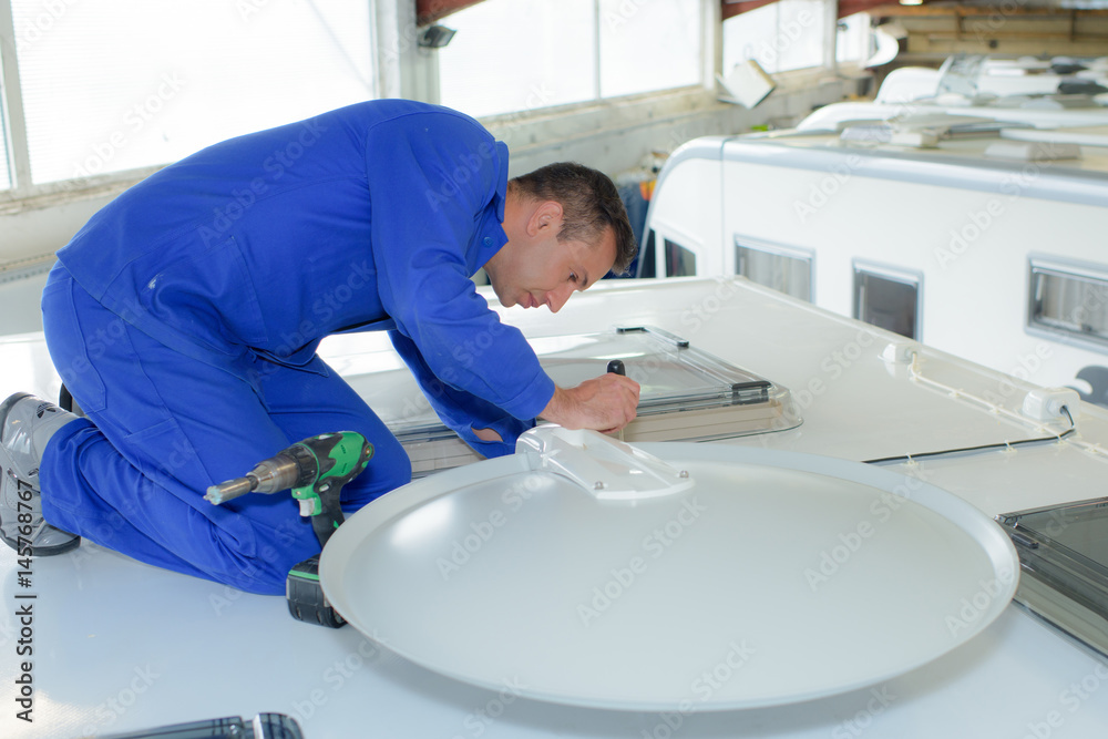 Fototapeta premium Mechanic fitting satellite dish to roof of camper van