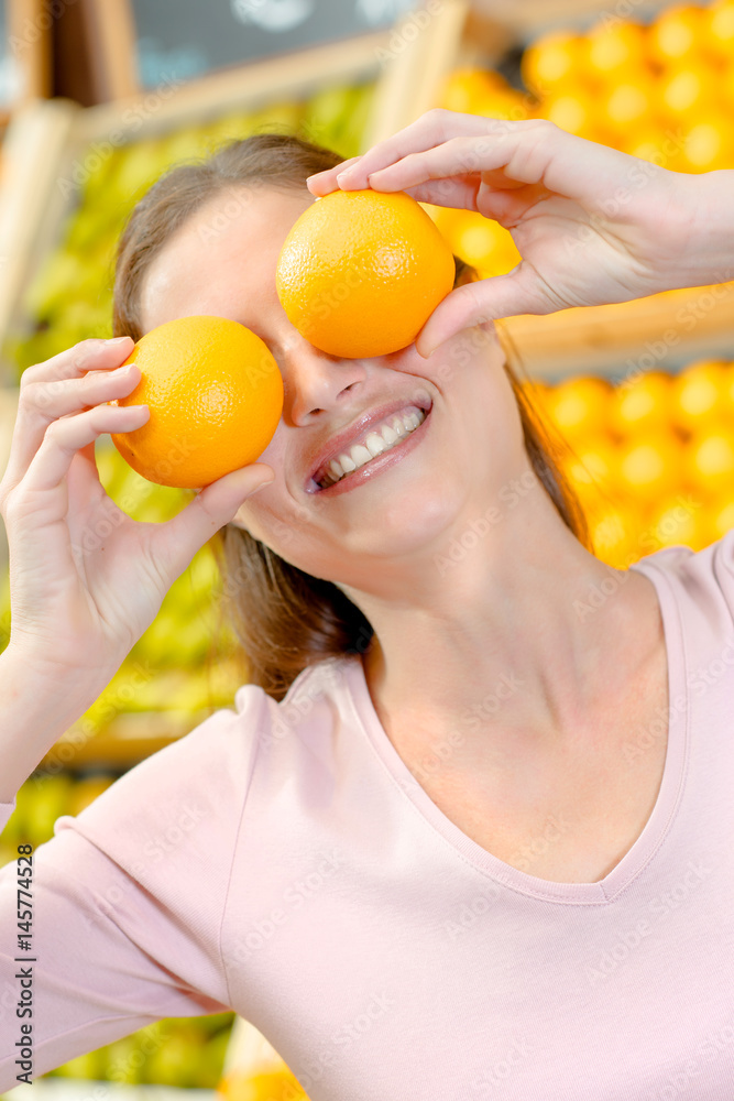 Playful woman covering her eyes with oranges Playful woman covering her eyes with oranges