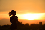 Silhouette of sporty fitness woman running at sunset