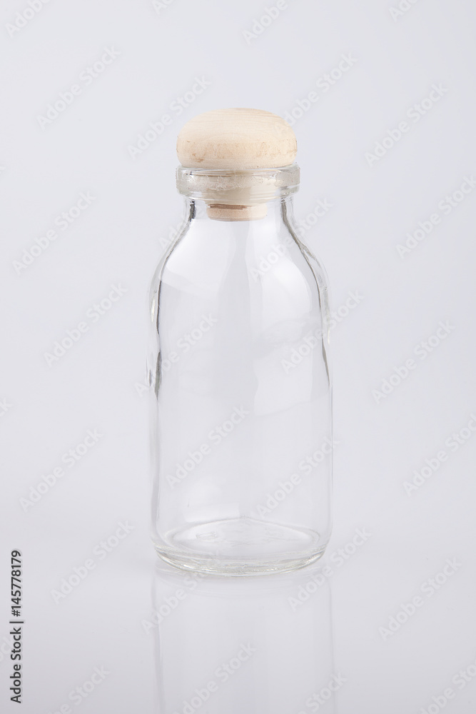 Clear glass empty bottle on a white surface. Bottle isolated on white background. Clear glass empty bottle on a white surface. Bottle isolated on white background.