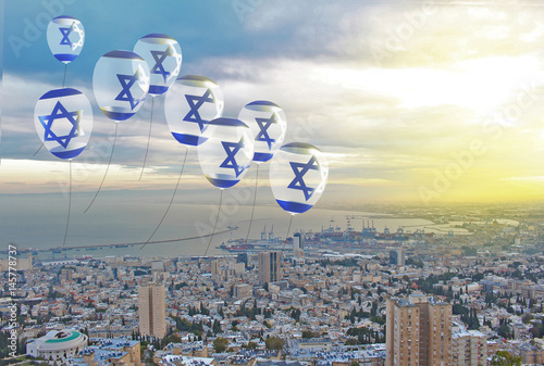Flag of Israel on air balloons against background of sunrise in Haifa. Ribbon in the colors of the flag are twisted under the balloon at Independence Day.