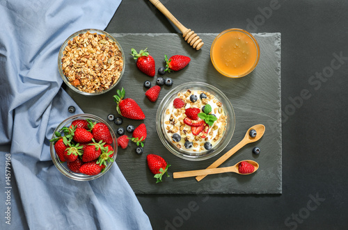 Breakfast of greek yogurt with berries, granola and honey.
