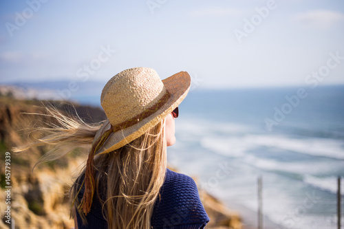 Young, blonde female, girl in a straw hat on the sun. California. Spring. Pacific ocean. California