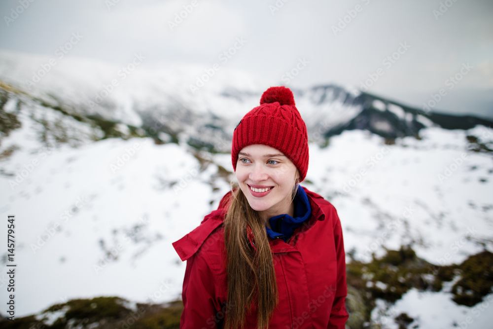 Portrait of girl in bright clothes on the background of winter mountains. Recreation fitness and healthy lifestyle outdoors in beautiful snowy nature.