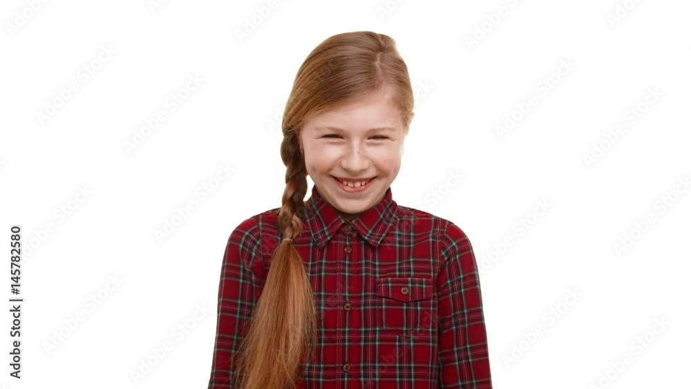Cute elementary-school aged girl with light brown plait of hair standing on white background and smiling laughing in slowmotion Cute elementary-school aged girl with light brown plait of hair standing on white background and smiling laughing in slowmotion