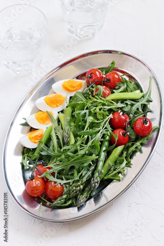 Asparagus salad with arugula  cherry tomatoes and eggs. Overhead view.