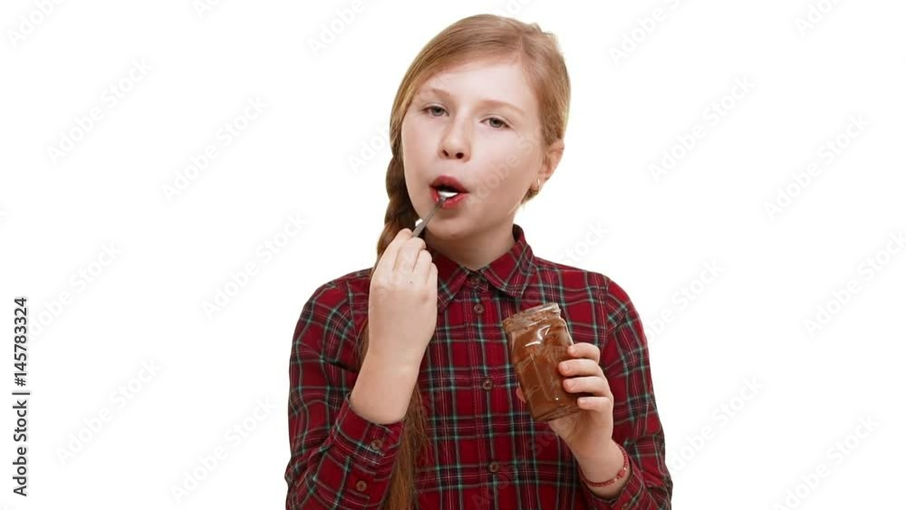 Cute elementary-school aged Caucasian girl with plait of hair eating chocolate spread with great excitement and pleasure standing on white background in slowmotion Cute elementary-school aged Caucasian girl with plait of hair eating chocolate spread with great excitement and pleasure standing on white background in slowmotion
