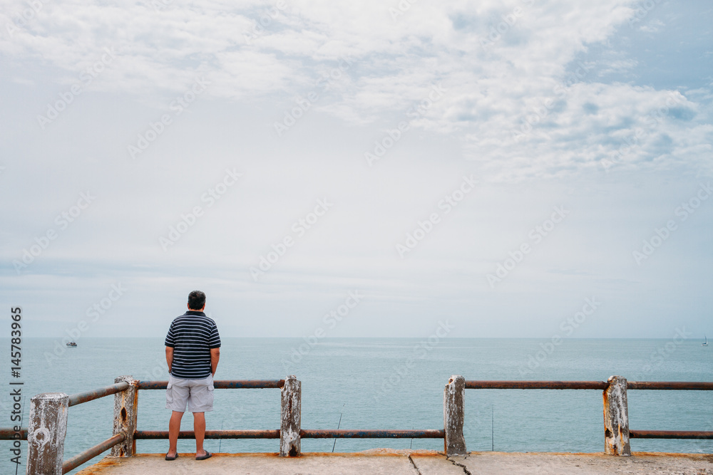 Single man standing in front of the sea on a balcony Single man standing in front of the sea on a balcony
