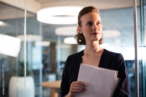 Businesswoman holdings documents while looking away