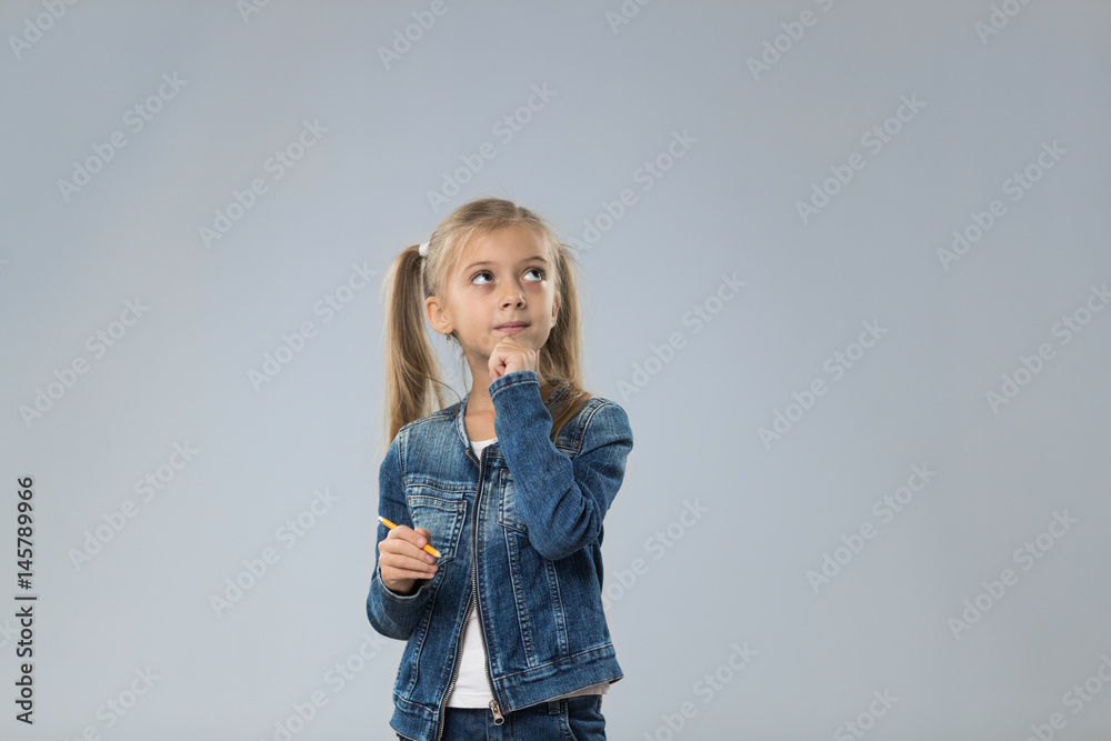 Little Teenage Girl In Jeans Coat, Small Kid Looking Up To Copy Space Think Hold Chin Isolated Over Gray Background Little Teenage Girl In Jeans Coat, Small Kid Looking Up To Copy Space Think Hold Chin Isolated Over Gray Background