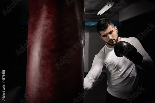 Handsome young man exercising with boxing gloves and punching bag