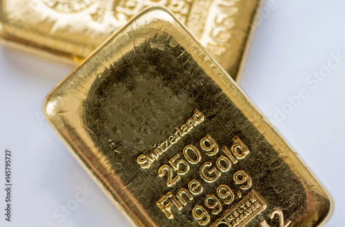Two cast gold bars. On a light background..