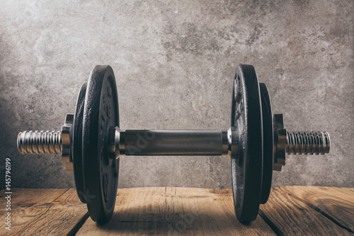  iron dumbbell on a wooden plank with gray background
