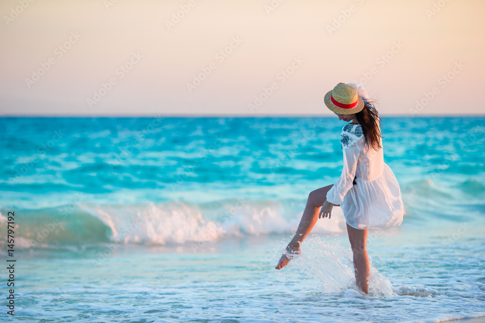 Young beautiful woman on tropical beach in sunset. Back view of young girl in beautiful dress background the sea Young beautiful woman on tropical beach in sunset. Back view of young girl in beautiful dress background the sea