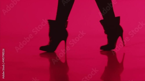 Woman walks in high heels in silhouette on red background