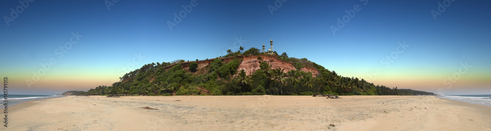 panoramic view of red colored stones cliff with mosque on top in Varkala, Kerala, India 