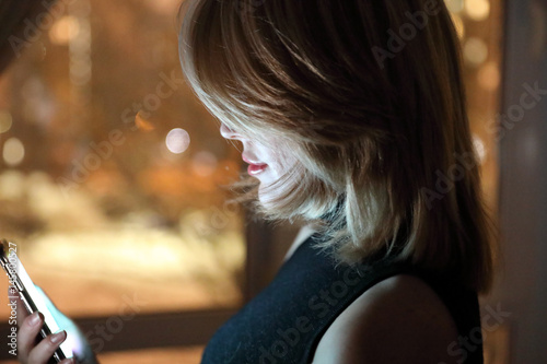 girl with smartphone near to window at night