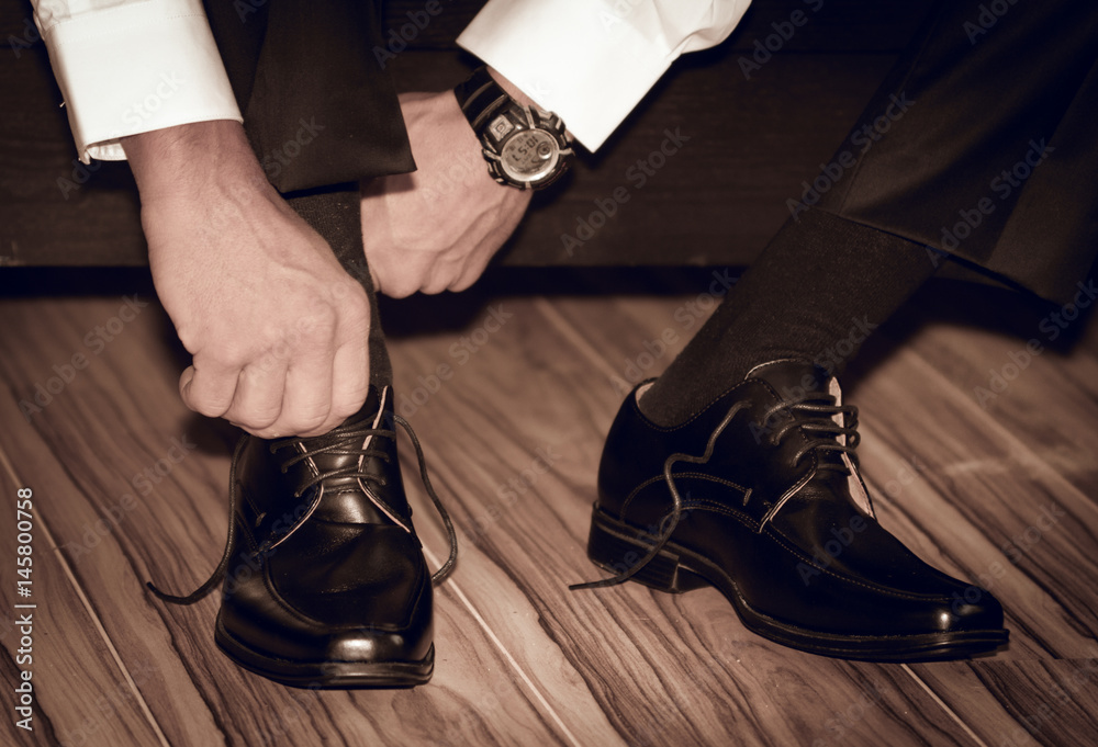 Groom wearing shoes on wedding day , tying the laces