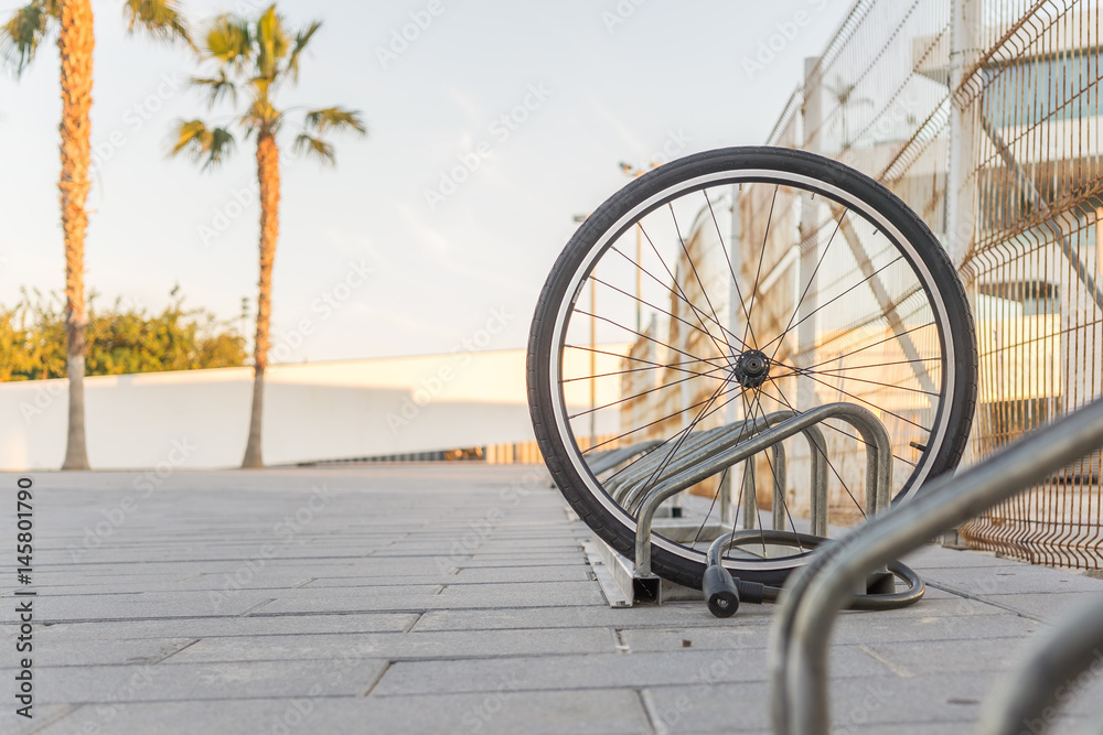 Stolen bicycle, Chained front bicycle wheel locked. A damaged bike wheel is all that is left, a single bicycle wheel on the street due to stealing. Stolen bicycle, Chained front bicycle wheel locked. A damaged bike wheel is all that is left, a single bicycle wheel on the street due to stealing.