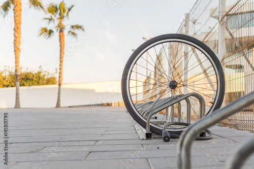 Stolen bicycle, Chained front bicycle wheel locked. A damaged bike wheel is all that is left, a single bicycle wheel on the street due to stealing. photo