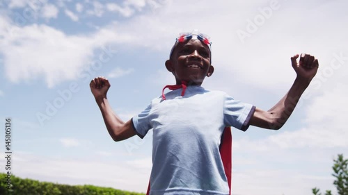 Two brothers dressed as firefighters play with a garden hose in their backyard.