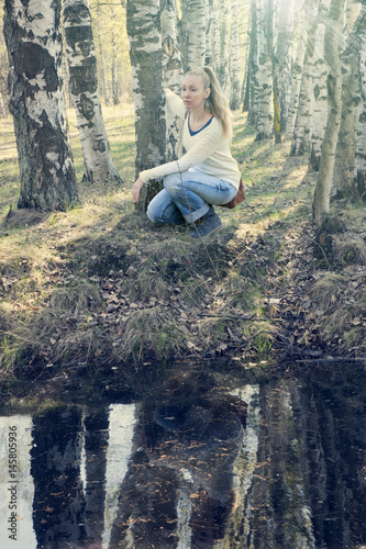 The young woman on the bank of the forest lake, toning