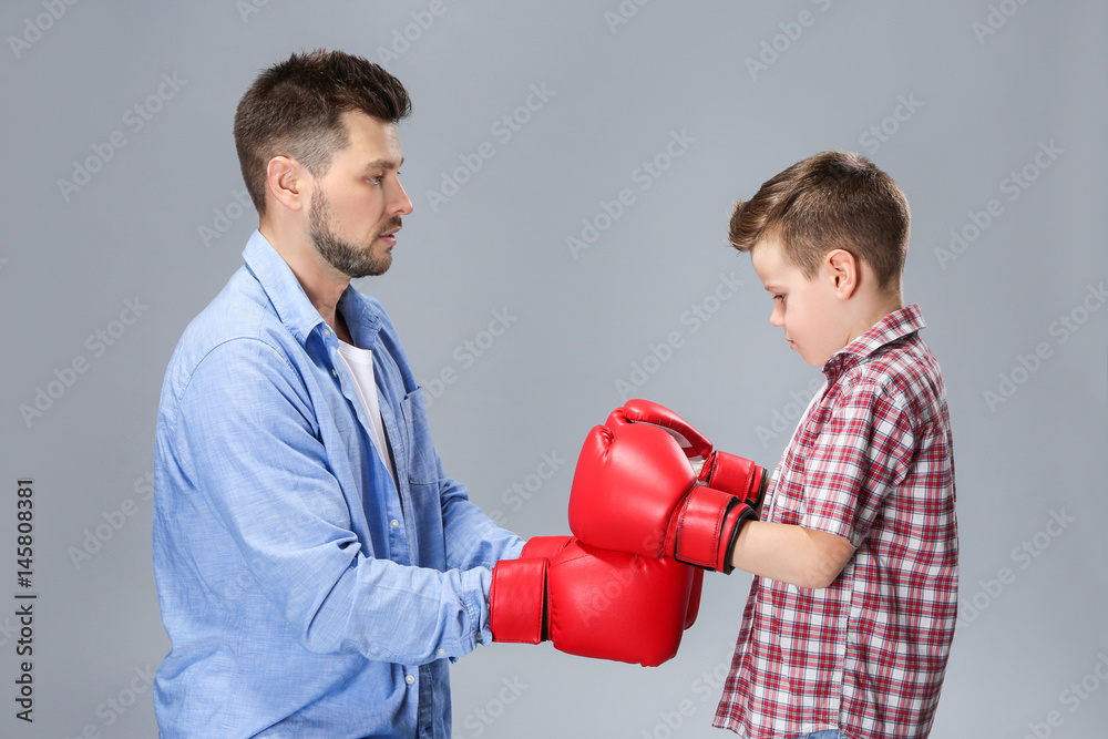 Father and son having boxing training on color background Father and son having boxing training on color background