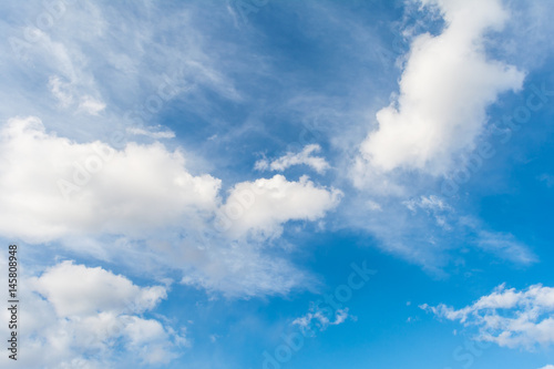 Blue sky with dense white cumulus clouds and transparent layered clouds