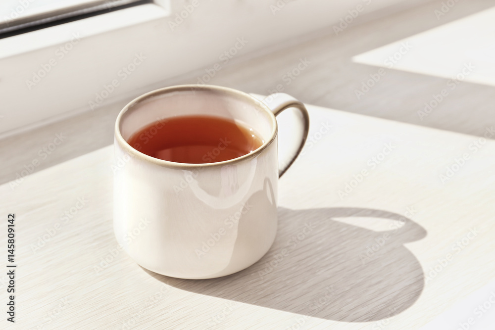Cup of hot tea on window sill, closeup Cup of hot tea on window sill, closeup