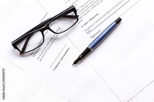 Signing the contract with pen and glasses in business work top view