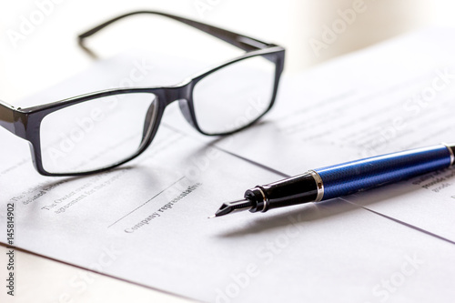 Signing the contract with pen and glasses in business work on office desk