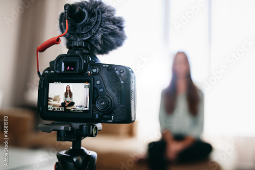 Young woman recording daily video blog on camera mounted on trip photo