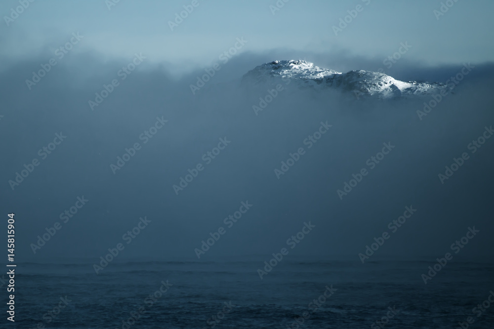 Mountain peak from clouds at Arctic Ocean Mountain peak from clouds at Arctic Ocean