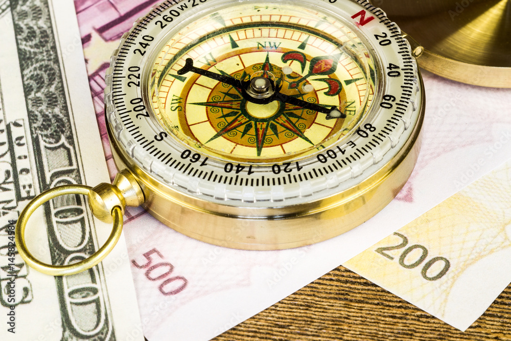Tourist compass with banknotes on wooden table Tourist compass with banknotes on wooden table