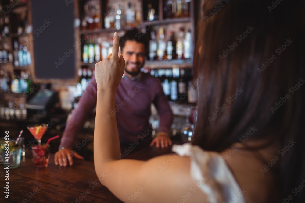 Woman asking for a drink to bar tender Woman asking for a drink to bar tender