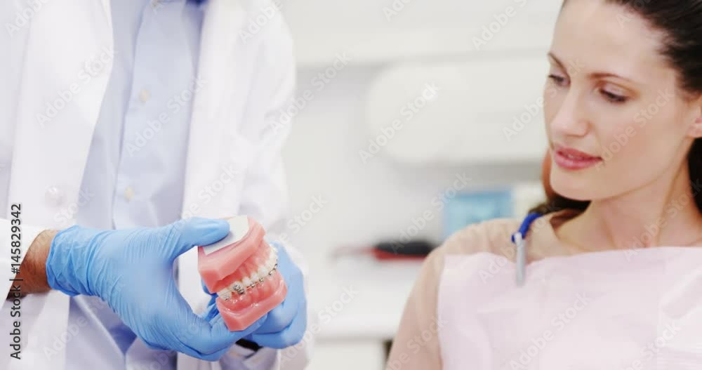 Dentist showing model teeth to patient Dentist showing model teeth to patient